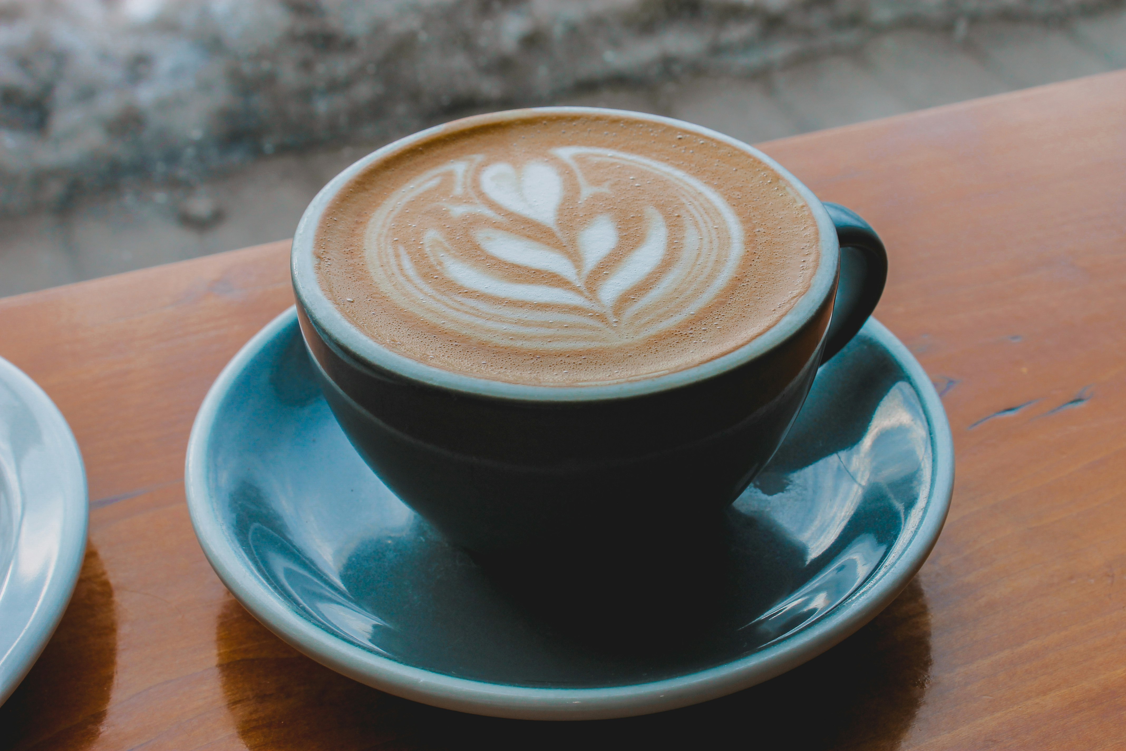 black ceramic cup with saucer on brown wooden table